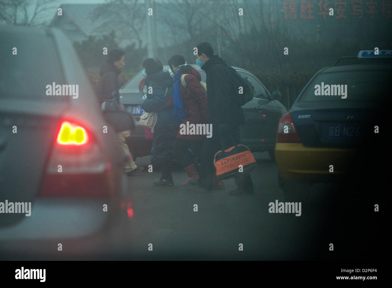 Fußgänger, die den Masken gehen unter Autos in dicker Nebel in Peking, China. 30. Januar 2013 Stockfoto