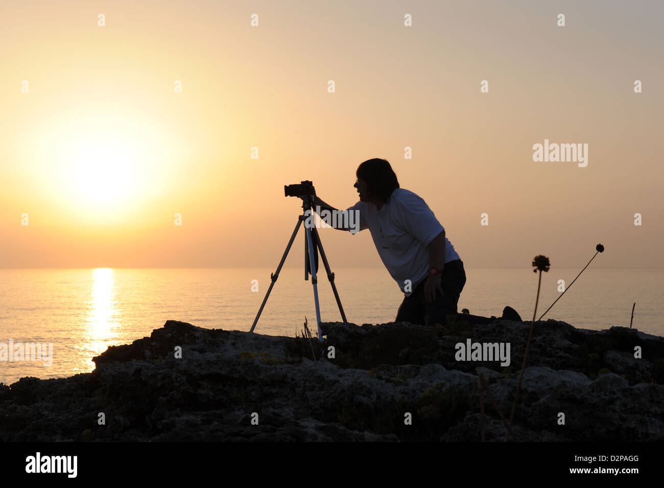 Silhouette eines Fotografen, die Bilder mit einem Stativ im Morgengrauen an der Küste von Menorca, Balearen, Spanien Stockfoto