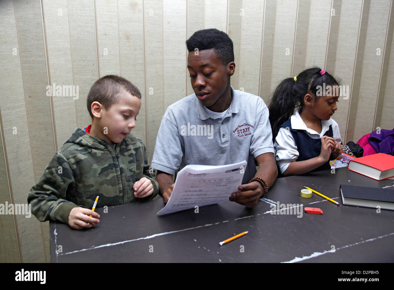 Alter Gymnasiast arbeitet mit jüngeren Kindern in ein pädagogisches Programm nach der Schule in New York City Stockfoto