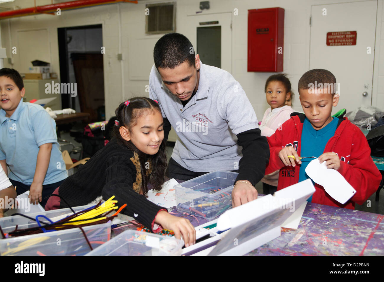 Alter Gymnasiast arbeitet mit jüngeren Kindern in ein pädagogisches Programm nach der Schule in New York City Stockfoto