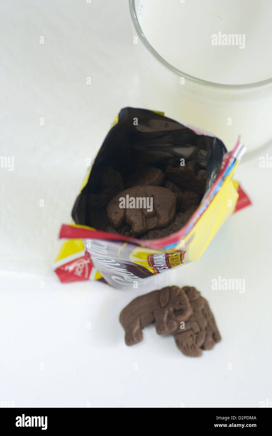 Tier geformt Schokoladenkekse mit Paket auf weißem Papierserviette und Glas der Kühe Milch Top Sicht Stockfoto