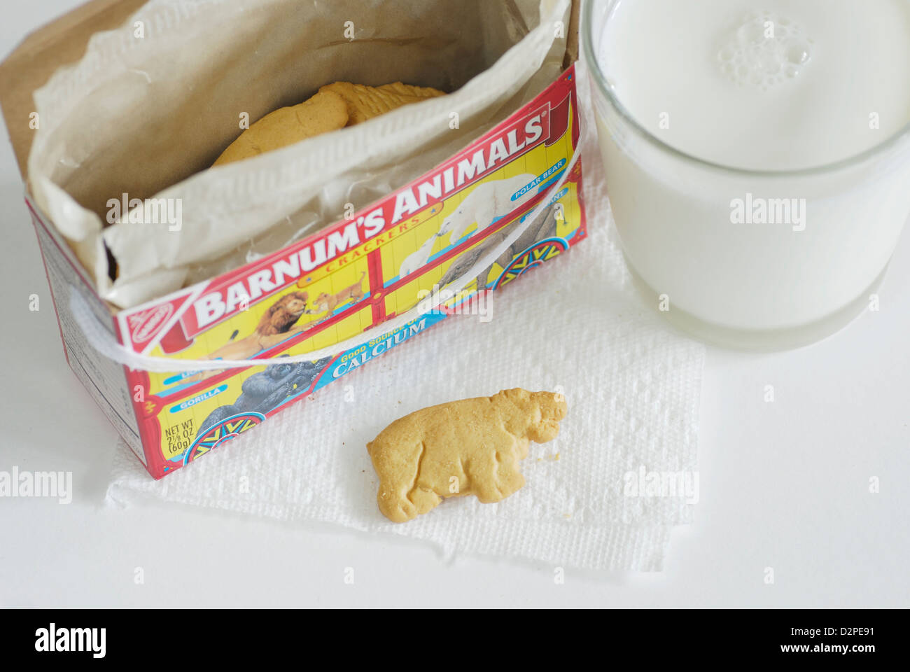 Animal Crackers mit Box und Glas Kuhmilch, Nilpferd, platziert am Tellerrand auf Serviette Stockfoto