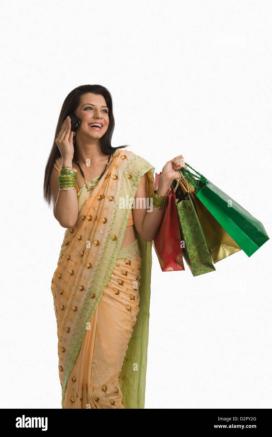 Frau telefonieren mit einem Handy und halten Einkaufstaschen Stockfoto