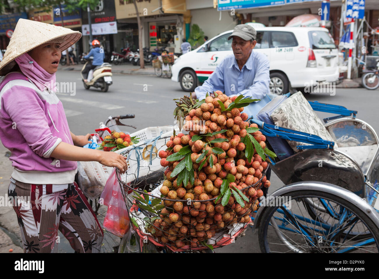 Ein Zyklus-Rikscha-Fahrer stoppt, um Obst zu kaufen, von einer Dame außerhalb Ben Thanh Market, Ho Chi Minh, Vietnam, Indochina Stockfoto