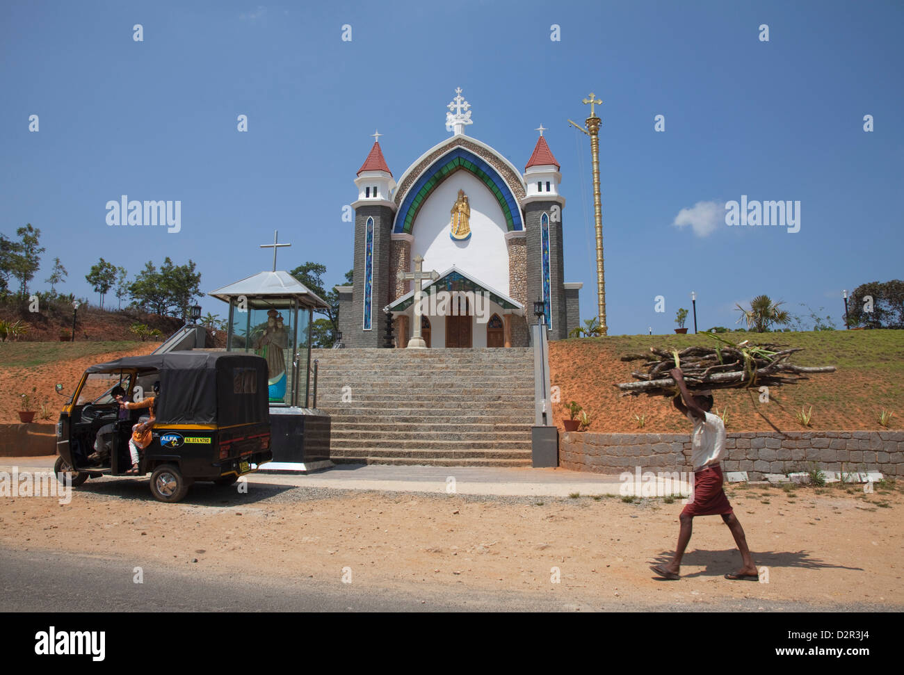 Mann mit Brennholz auf seinem Kopf, vorbei an einer Kirche in ländlichen Kerala, Indien, Asien Stockfoto