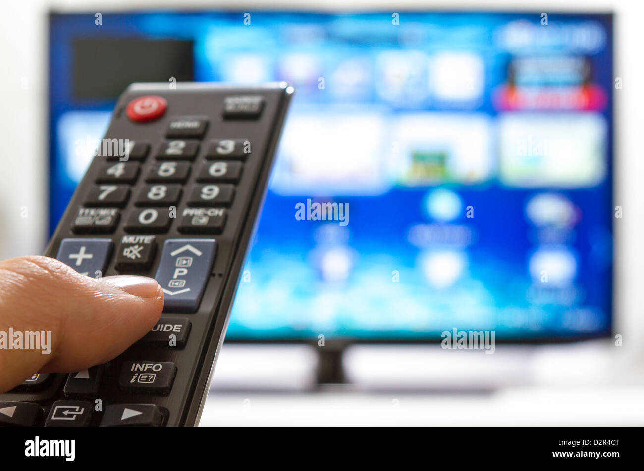 TV-Fernbedienung wechselt Kanäle Daumen auf dem blauen Bildschirm Stockfoto