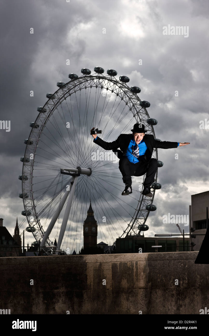 Parkour-Läufer in vollständigen Anzug springen vor London eye Stockfoto