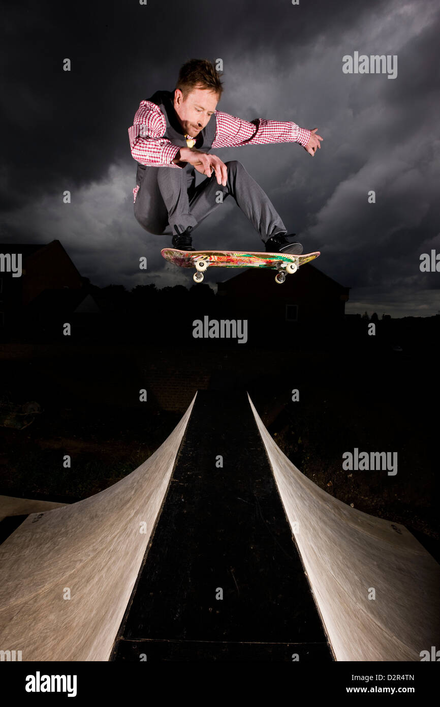 Geschäftsmann zu riskieren, springen über Skate-Rampe Stockfoto