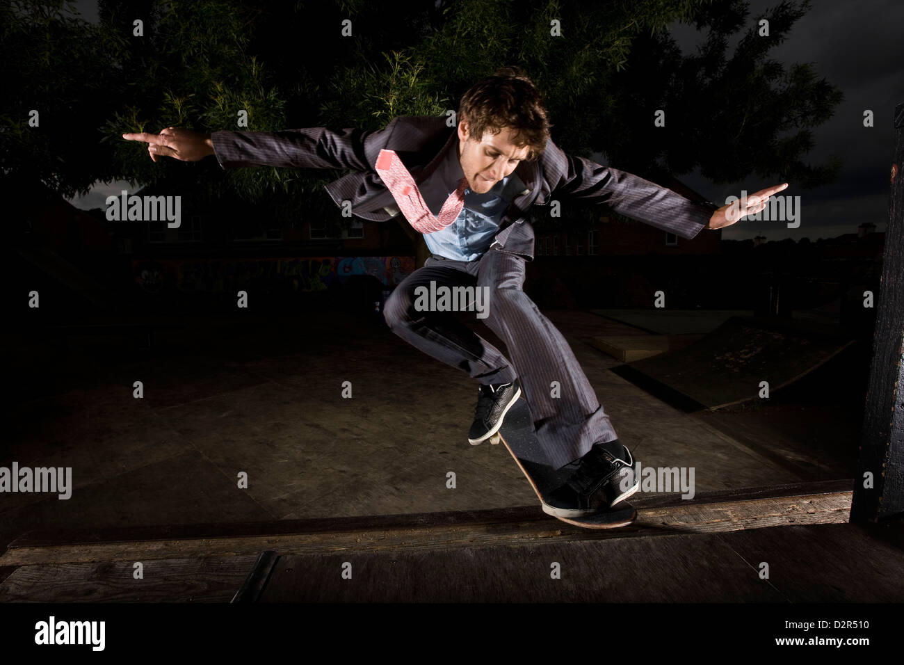 Mann im Anzug skateboarding in der Nacht Stockfoto