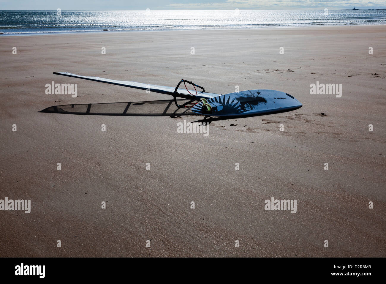 Ein Surfbrett im niedrigen Morgenlicht am sandigen Strand von Blyth macht interessante Formen und Schatten, Northumberland UK Stockfoto