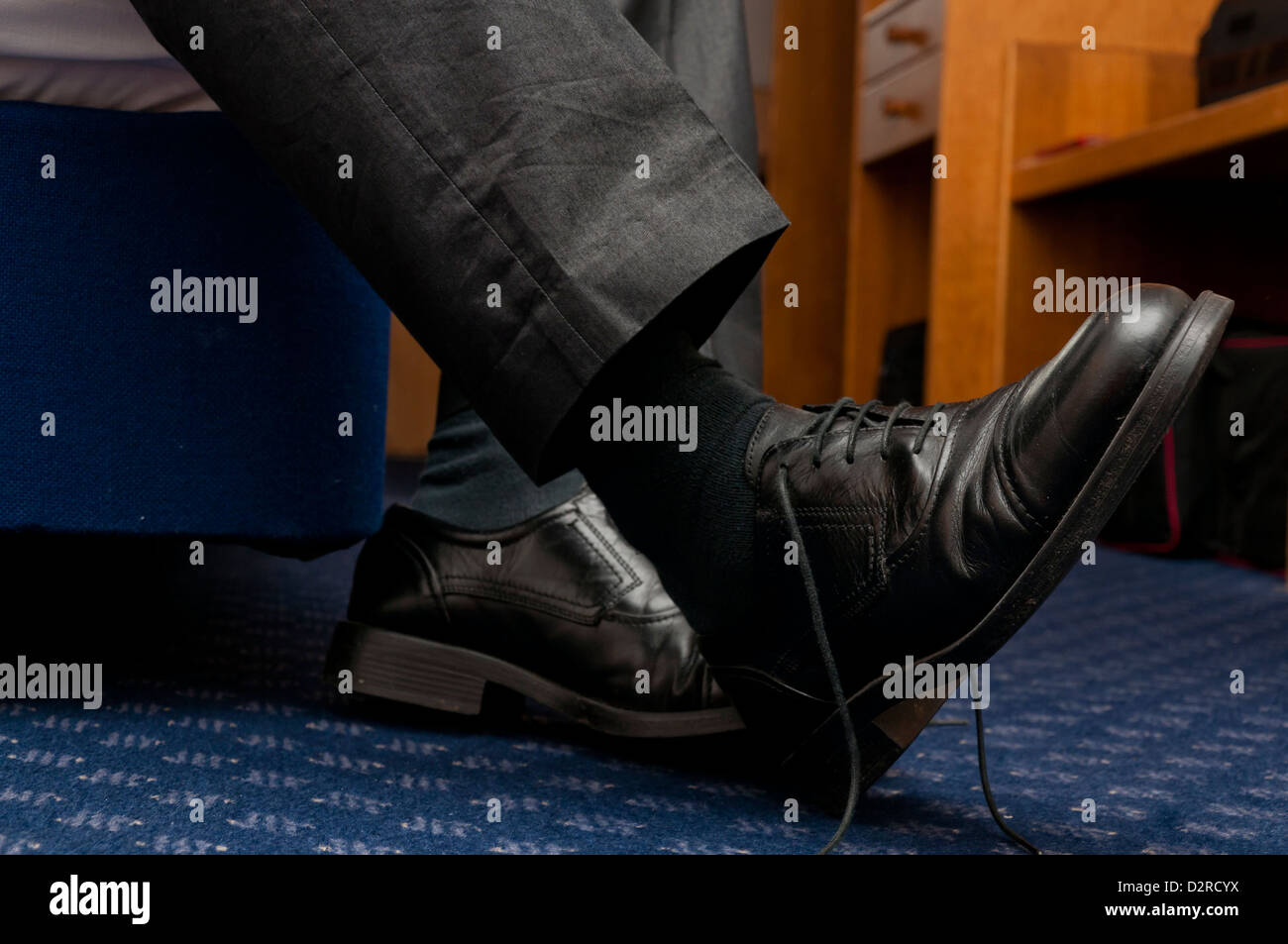 Ein müder Geschäftsmann, der die Schuhe im Hotelzimmer auszieht Stockfoto