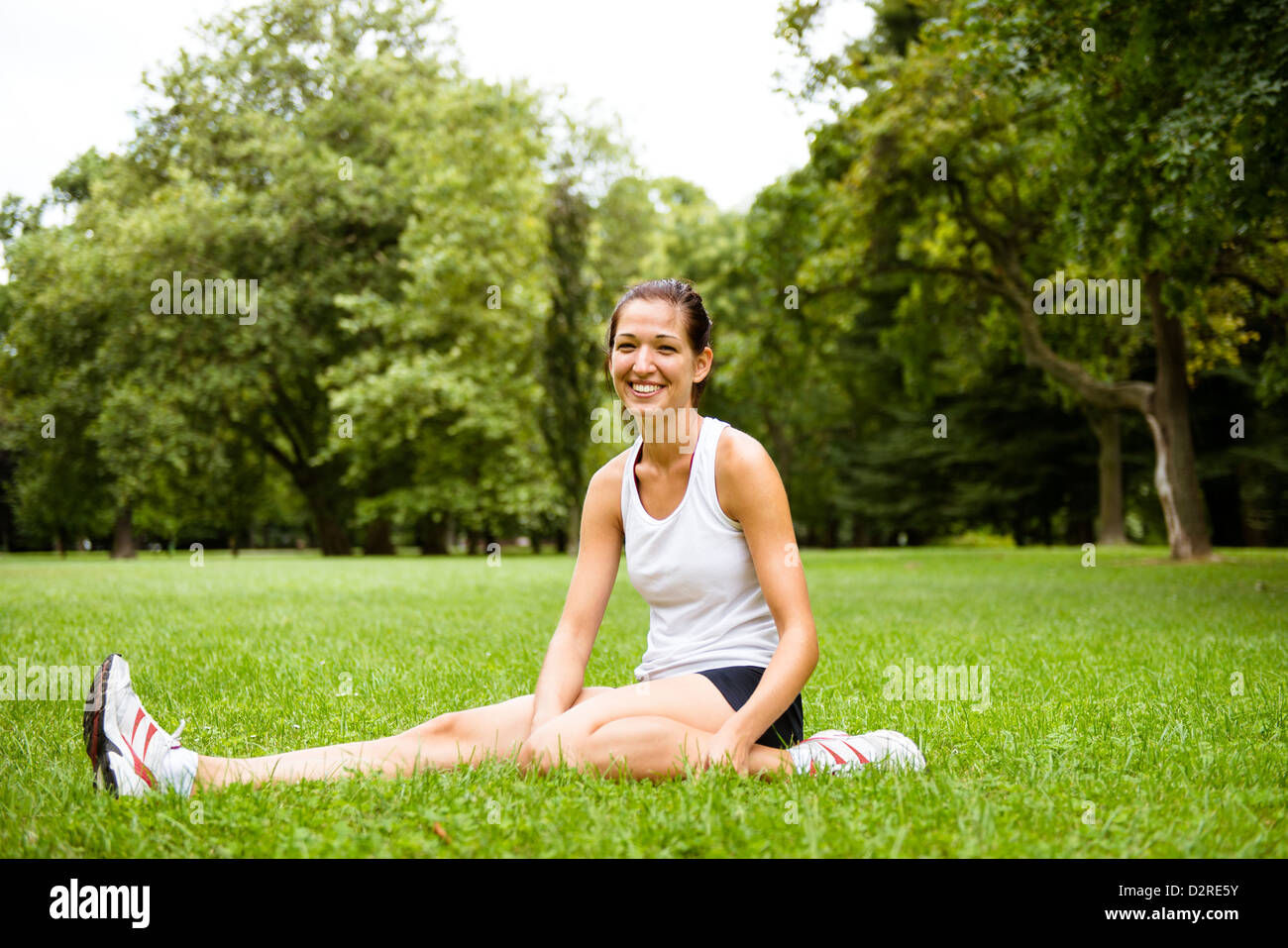 Junge lächelnde Fitness Frau dehnen Sie Muskeln vor sportlichen Aktivitäten Stockfoto