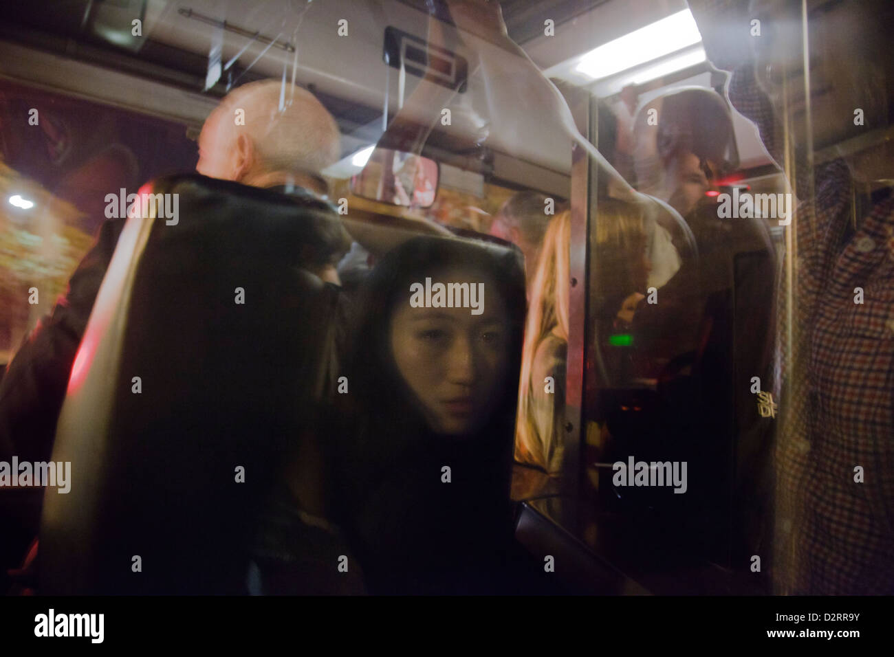 Asiatische Frau spiegelt sich in das Fenster hinter dem Fahrer eines überfüllten Bus in Paris Stockfoto