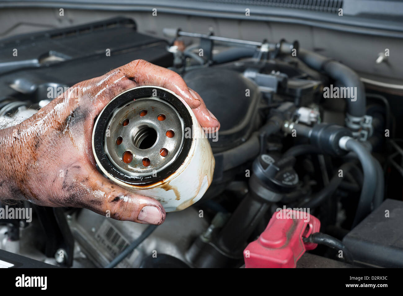 Kfz-Mechaniker zeigt einen alten, schmutzigen Ölfilter nur entfernt von einem Auto während der allgemeinen Wartung Stockfoto