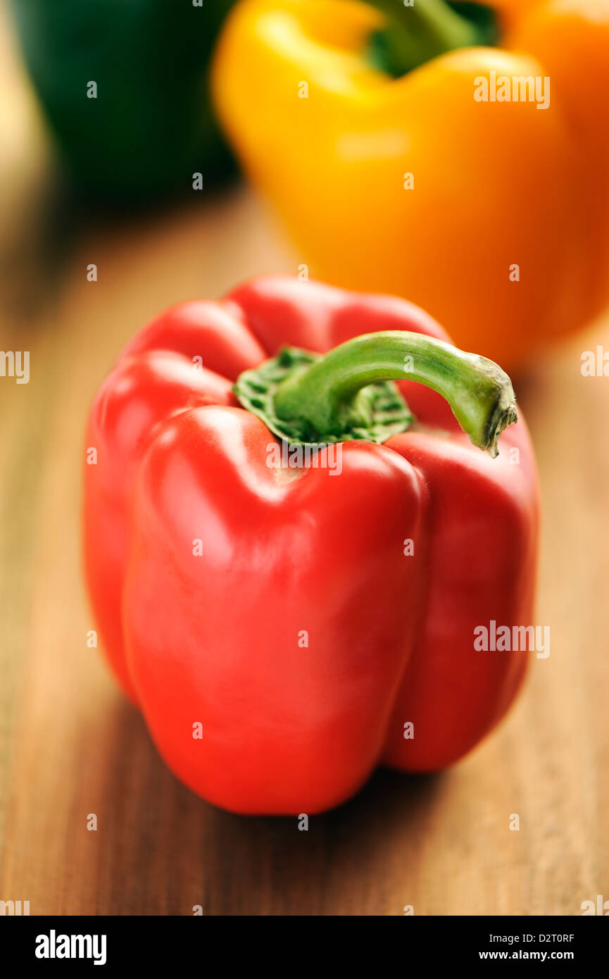 Rote, gelbe und grüne Paprika auf einem hölzernen Hintergrund. Stockfoto