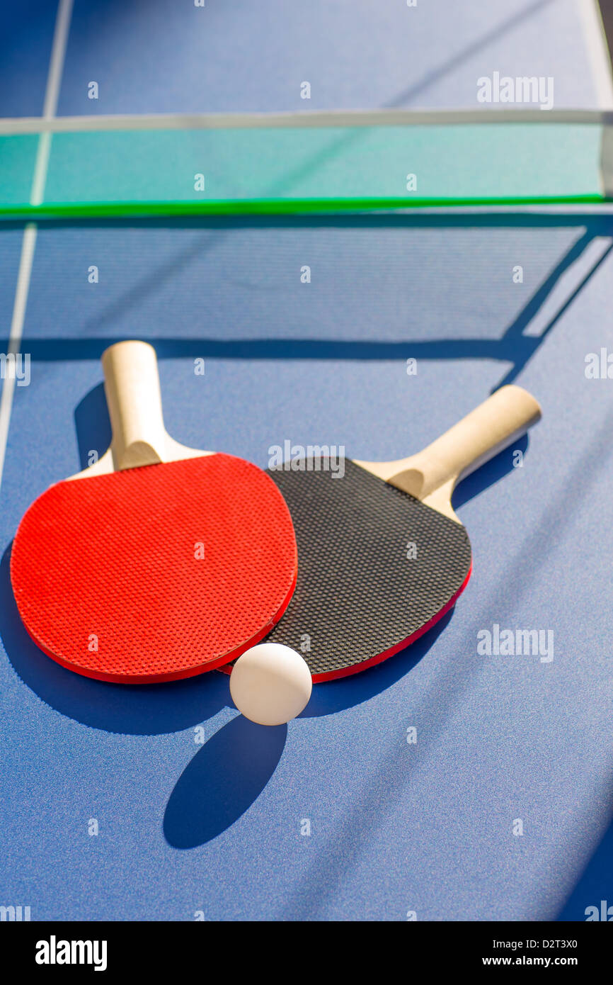 Tischtennis Ping Pong zwei Paddel und weiße Kugel auf blauen Brett Stockfoto