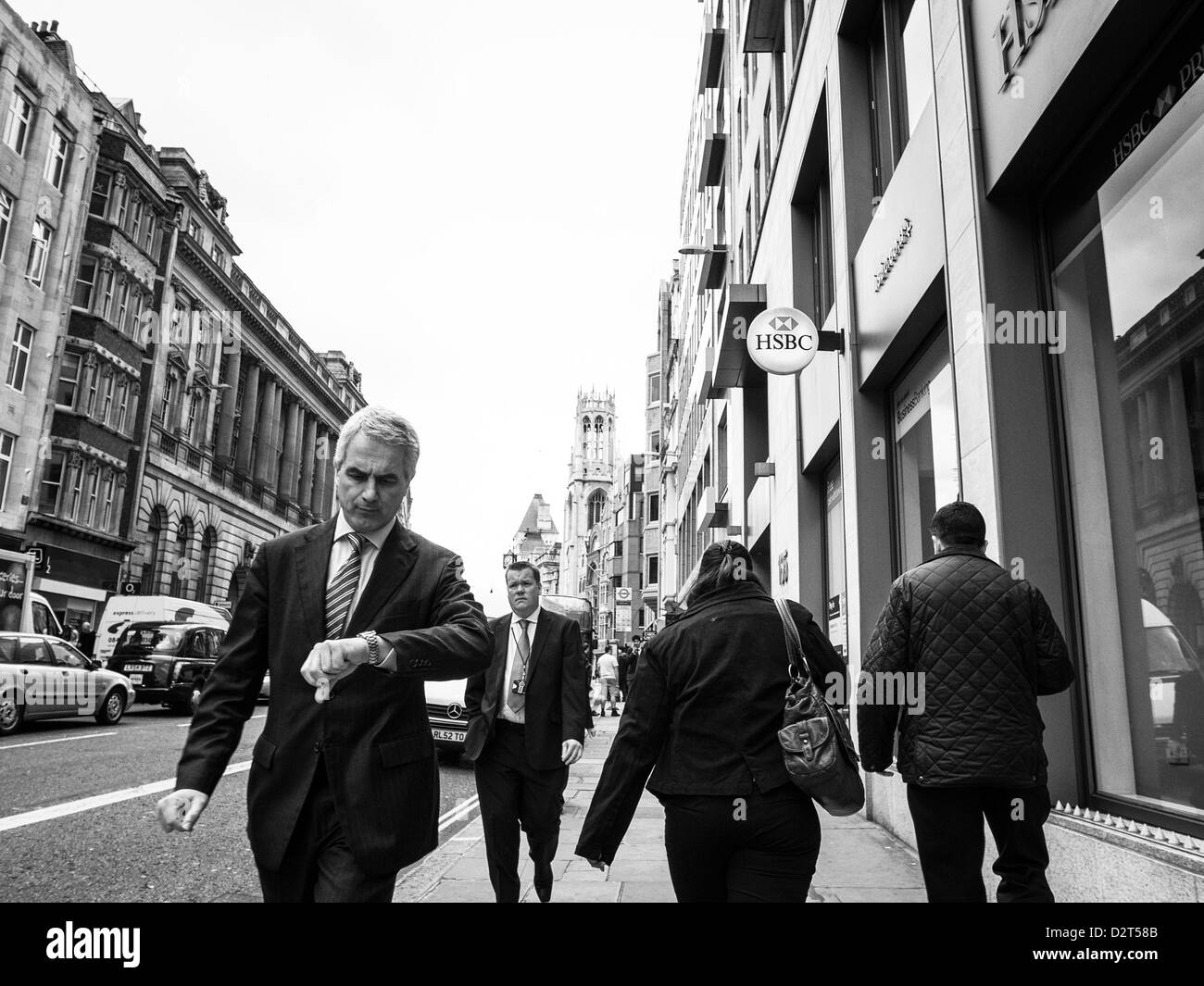 Bussinessman im Anzug Überprüfung Zeit zu Fuß auf einer Straße von HSBC bank Stockfoto
