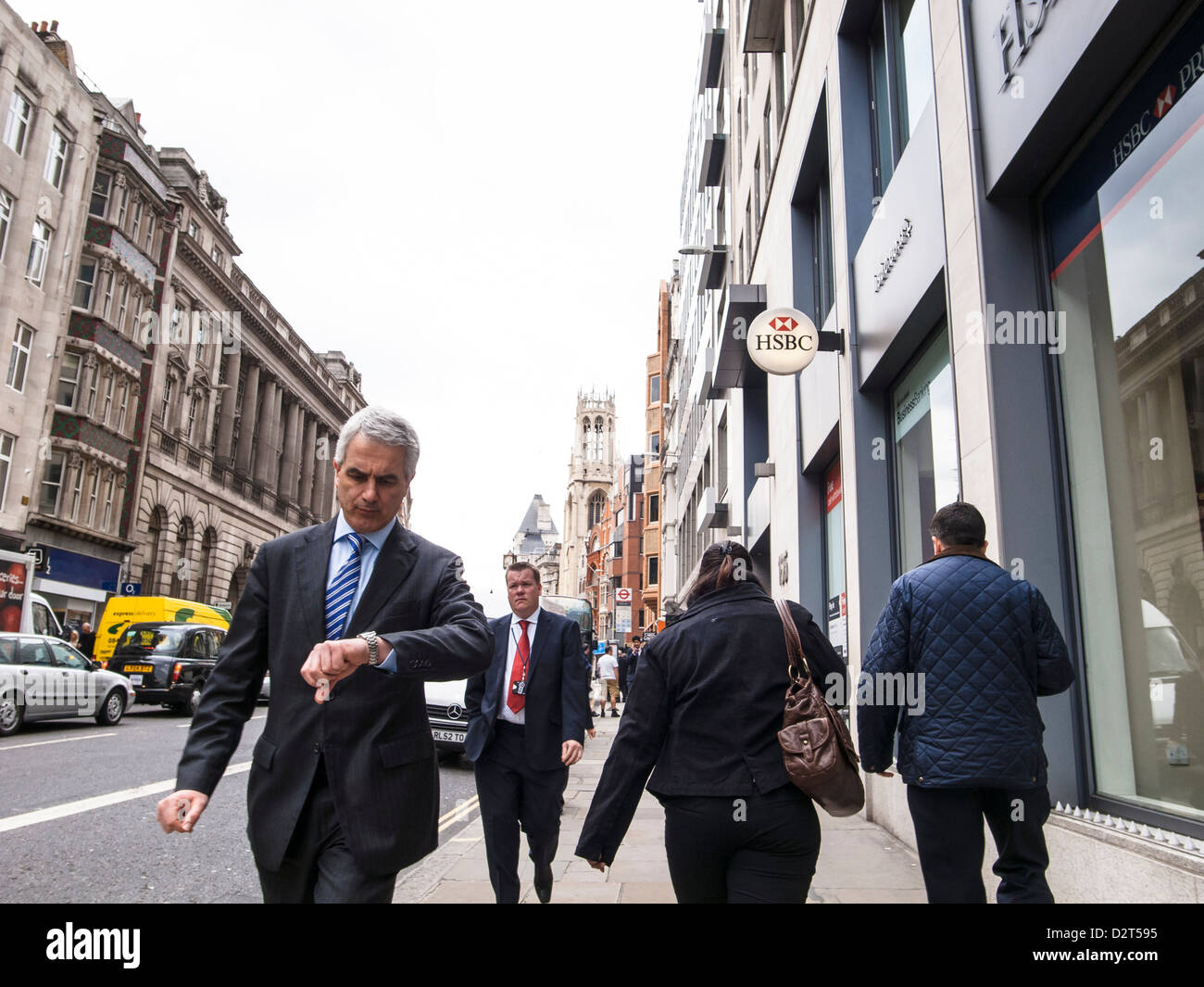 Geschäftsmann im Anzug Überprüfung Zeit zu Fuß auf einer Straße von HSBC bank Stockfoto