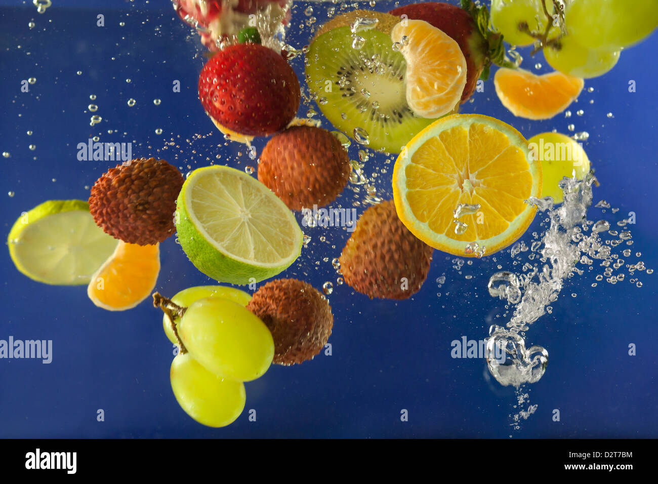Obst spritzen im Wasser mit Luftblasen vor blauem Hintergrund Stockfoto