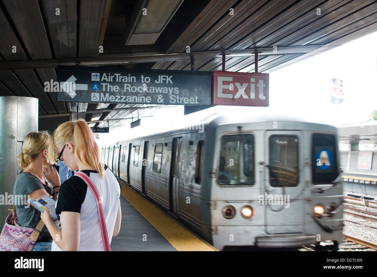 New York. Ein u-Bahn-Zug rollt in eine Station, wie zwei Frauen auf der Plattform warten Stockfoto