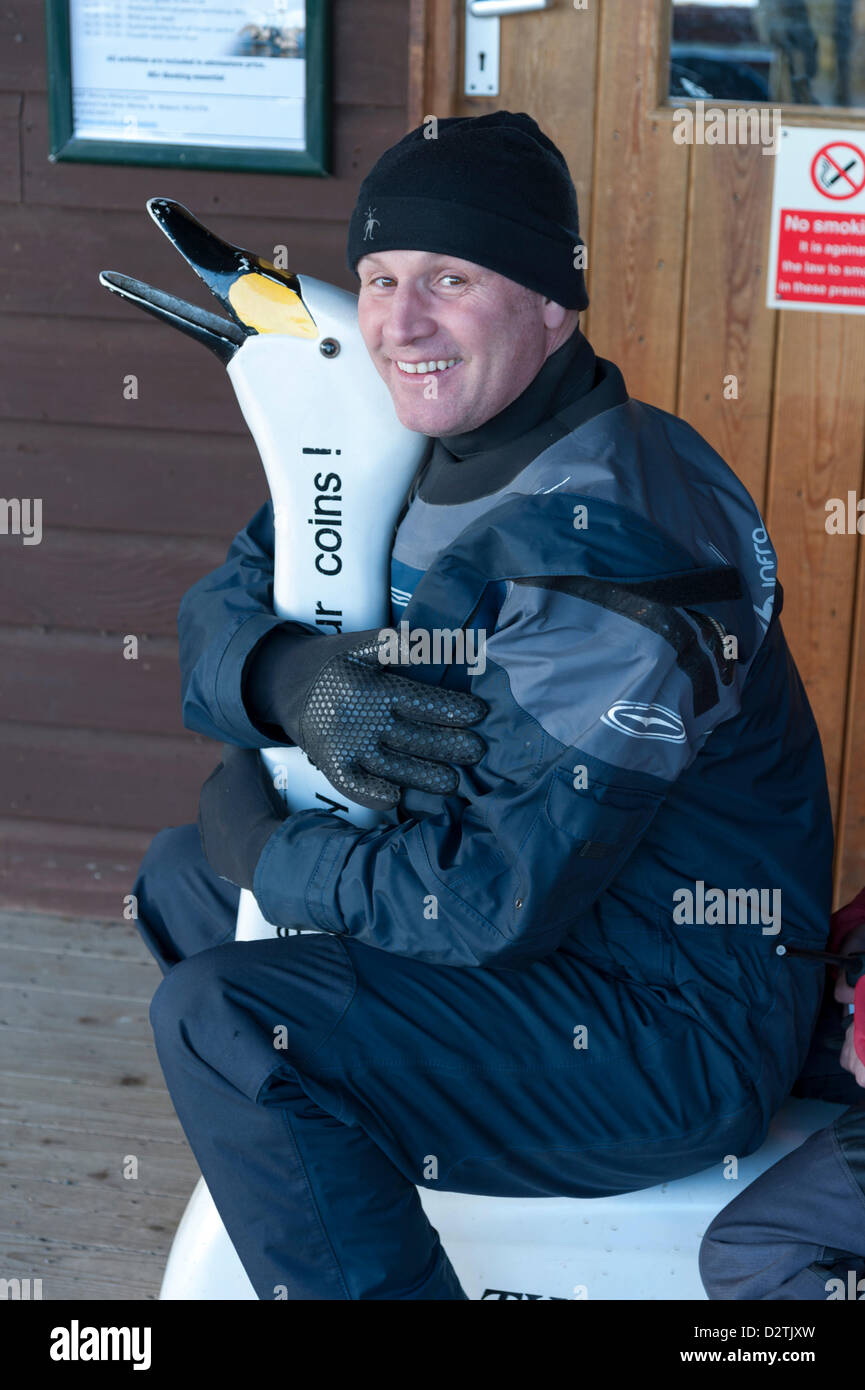 TV-Moderator Mike Dilger dons einen Trockentauchanzug um Schwäne und Federwild am Federwild und Feuchtgebiete Vertrauen auf Welney, Norfolk, Großbritannien zu füttern. 1. Februar 2013. Es ist World Wetlands Day am Samstag, 2. Februar, eine Veranstaltung, die seit 1997, Bewusstsein für den Wert der Feuchtgebiete zu fördern.  Mike ist ein "Big 9 Challenge" besuchen alle Wildfowl und Feuchtgebiet vertraut UK Websites in 9 Tagen abschließen.  Welney Tag 8 war und musste ins Wasser waten, wie der Ouse wäscht durch den letzten Schnee schmelzen und Regen überflutet wurden. Waschungen sind Heimat von Tausenden von Schwänen und Vögel, die für den Winter zu migrieren. Stockfoto