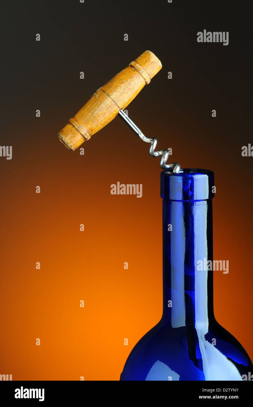 Alter Korkenzieher in blauen Flasche Wein über ein warmes Licht auf dunklem Hintergrund. Stockfoto