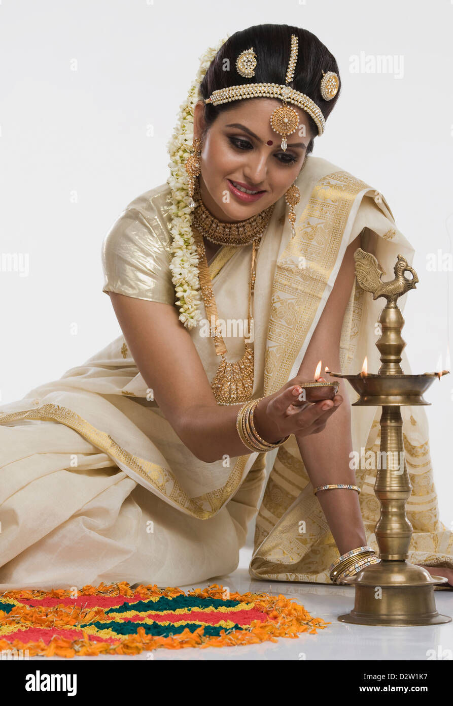 Indische Frau in traditioneller Kleidung, die Beleuchtung einer Öllampe Stockfoto