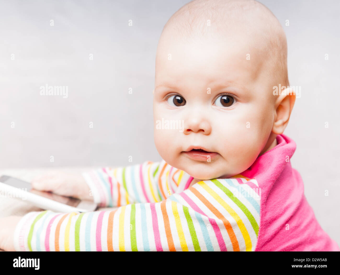Kleines Baby in bunt gestreiften Kleidung mit Handy Stockfoto