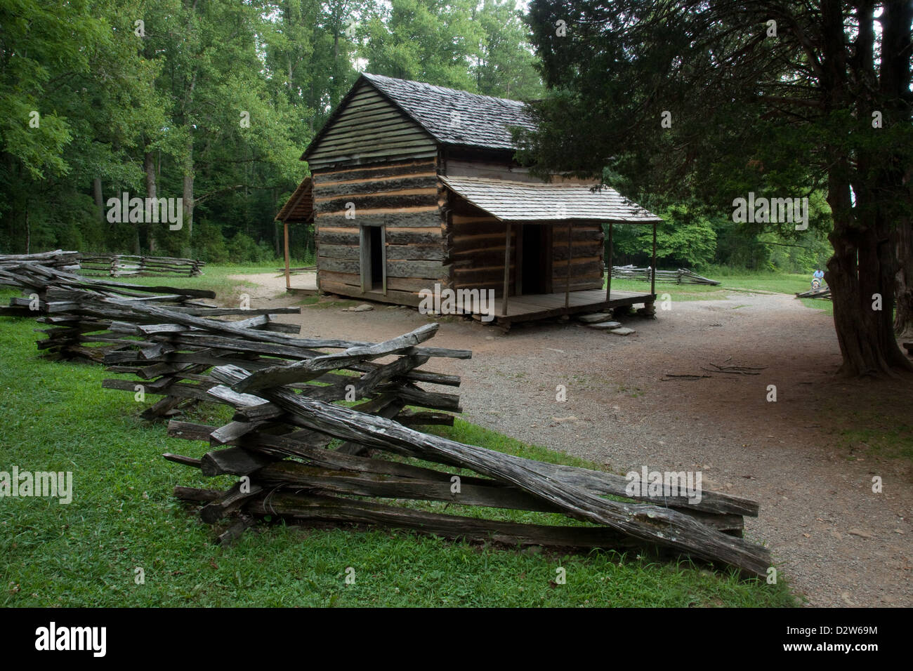 Alte rustikale Blockhütte im Wald mit einem Split Zaun daneben Stockfoto