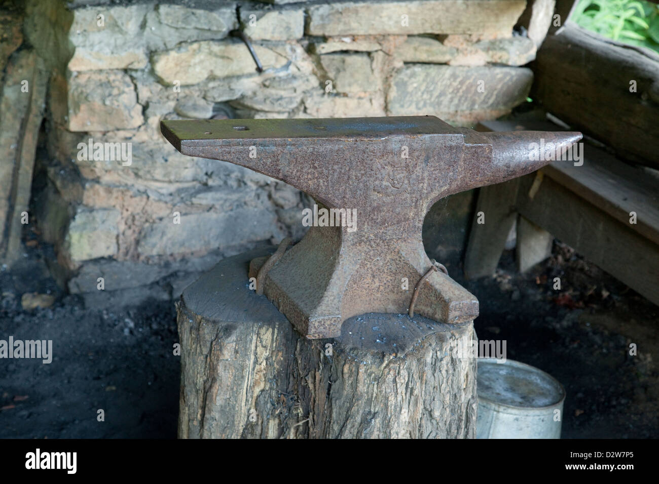 Metall Amboss mit Rost befestigt auf einem Baumstumpf und einer Steinmauer im Hintergrund Stockfoto