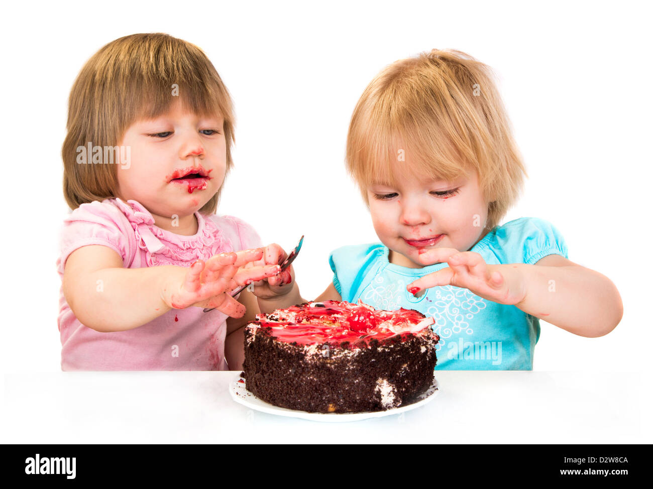 Zwei kleine Baby Mädchen essen Kuchen weißen Hintergrund isoliert Stockfoto