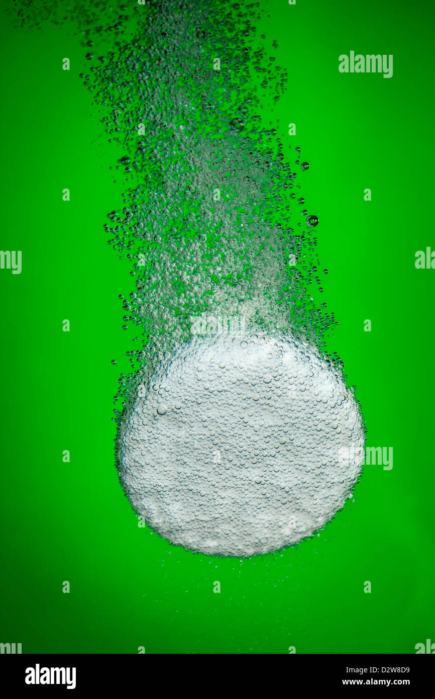 Brausetablette in Wasser mit Luftblasen auf einem grünen Hintergrund Stockfoto