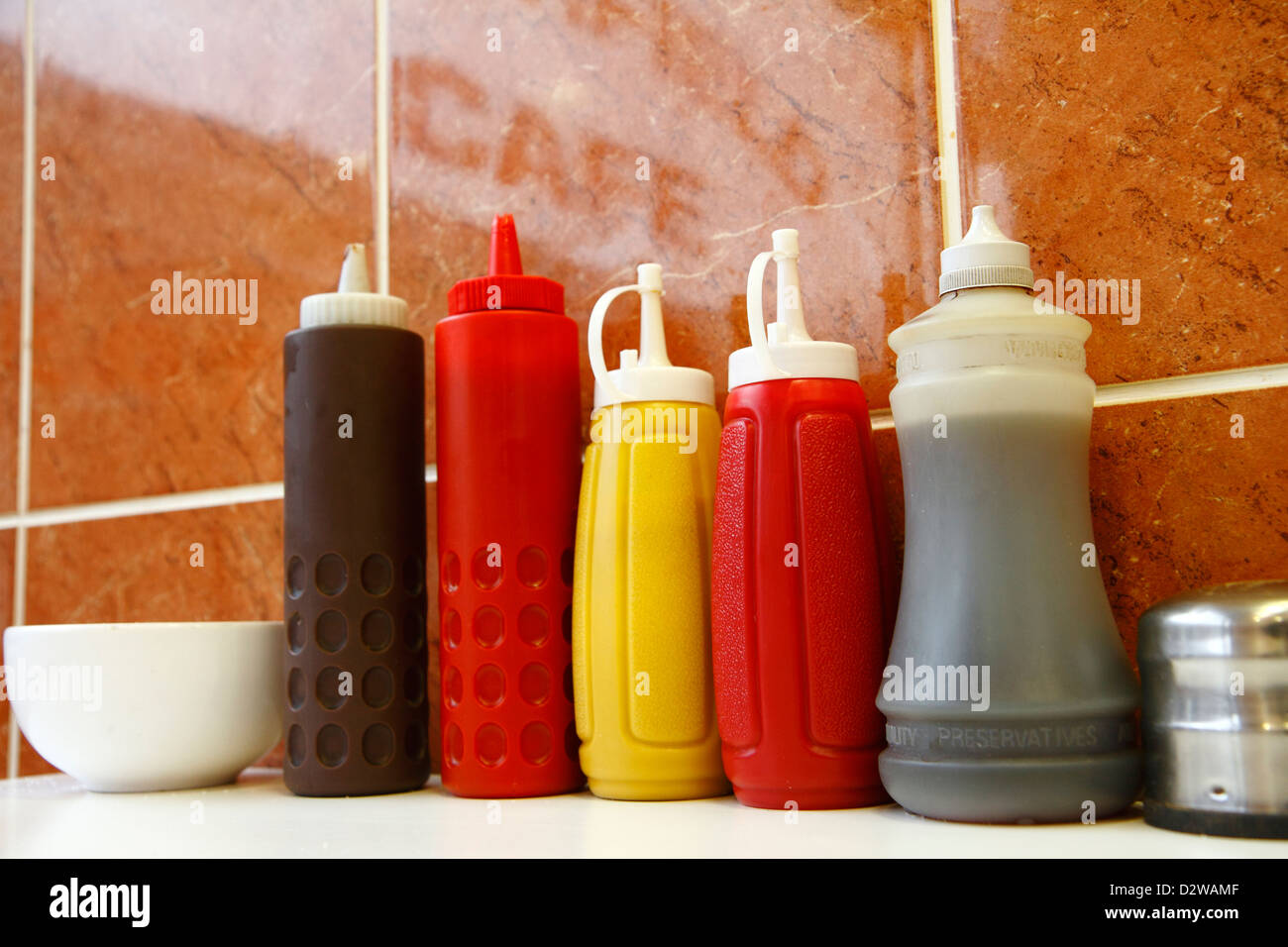Kunststoff-Gewürz-Flaschen (Ketchup, braune Sauce, Senf, Essig) im Café, London. Stockfoto