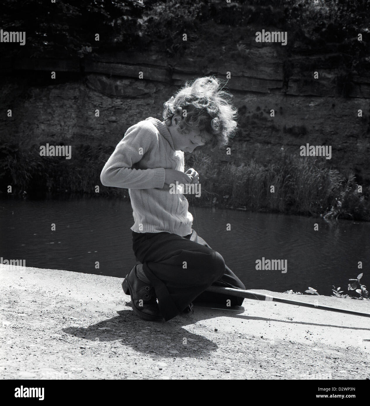 Ein britischer Junge mit einer Angelrute, die sich konzentriert niederkniet Beim Setzen eines Wurms auf einem Angelhaken für Köder Entlang der Leeds & Liverpool Kanal in 1970s West Yorkshire England Großbritannien Großbritannien 1974 KATHY DEWITT Stockfoto