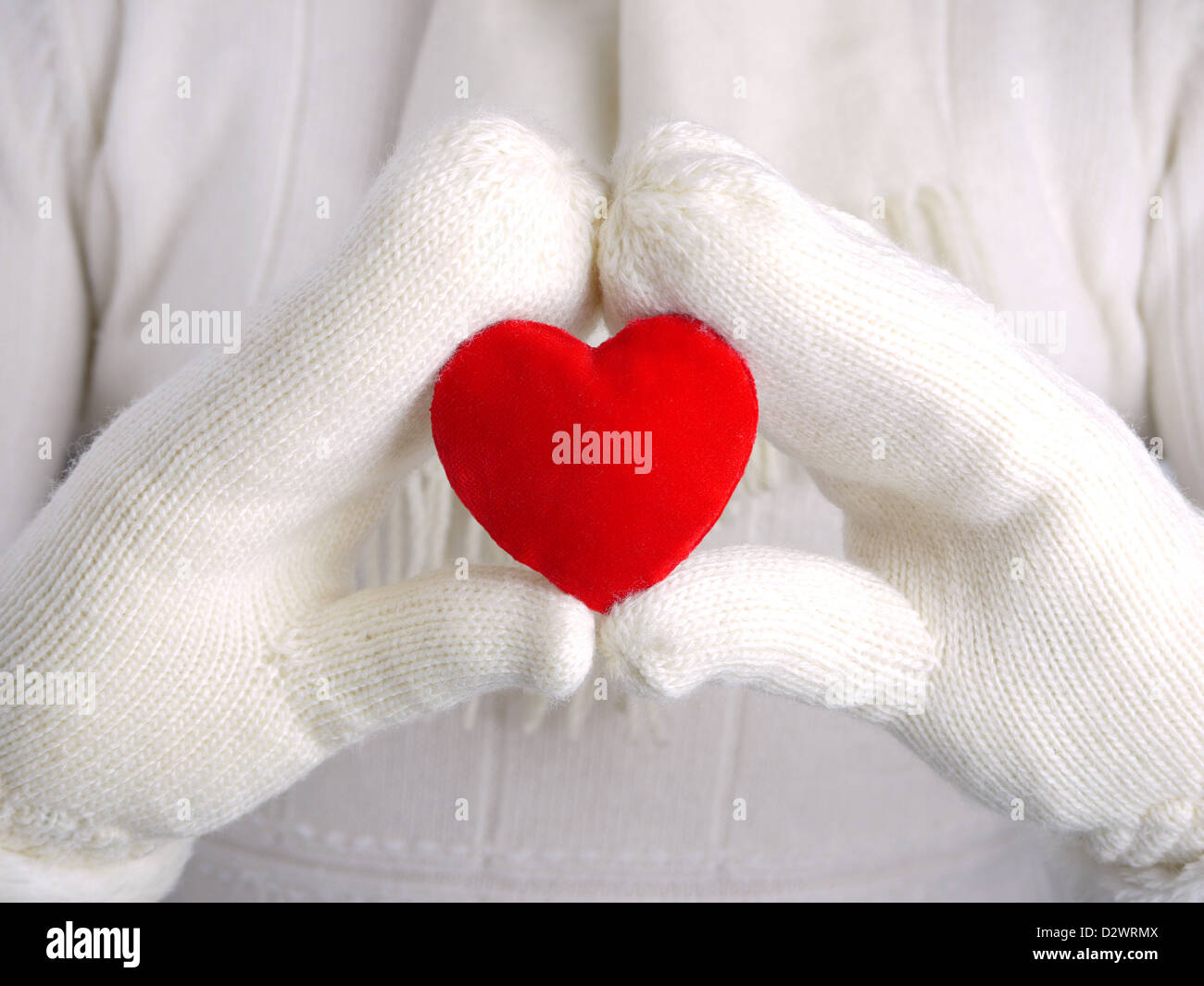 Nahaufnahme von weiblichen Händen tragen weiße warme Wolle Handschuhe halten lesen Wildleder Herz als Valentinstag-Konzept Stockfoto