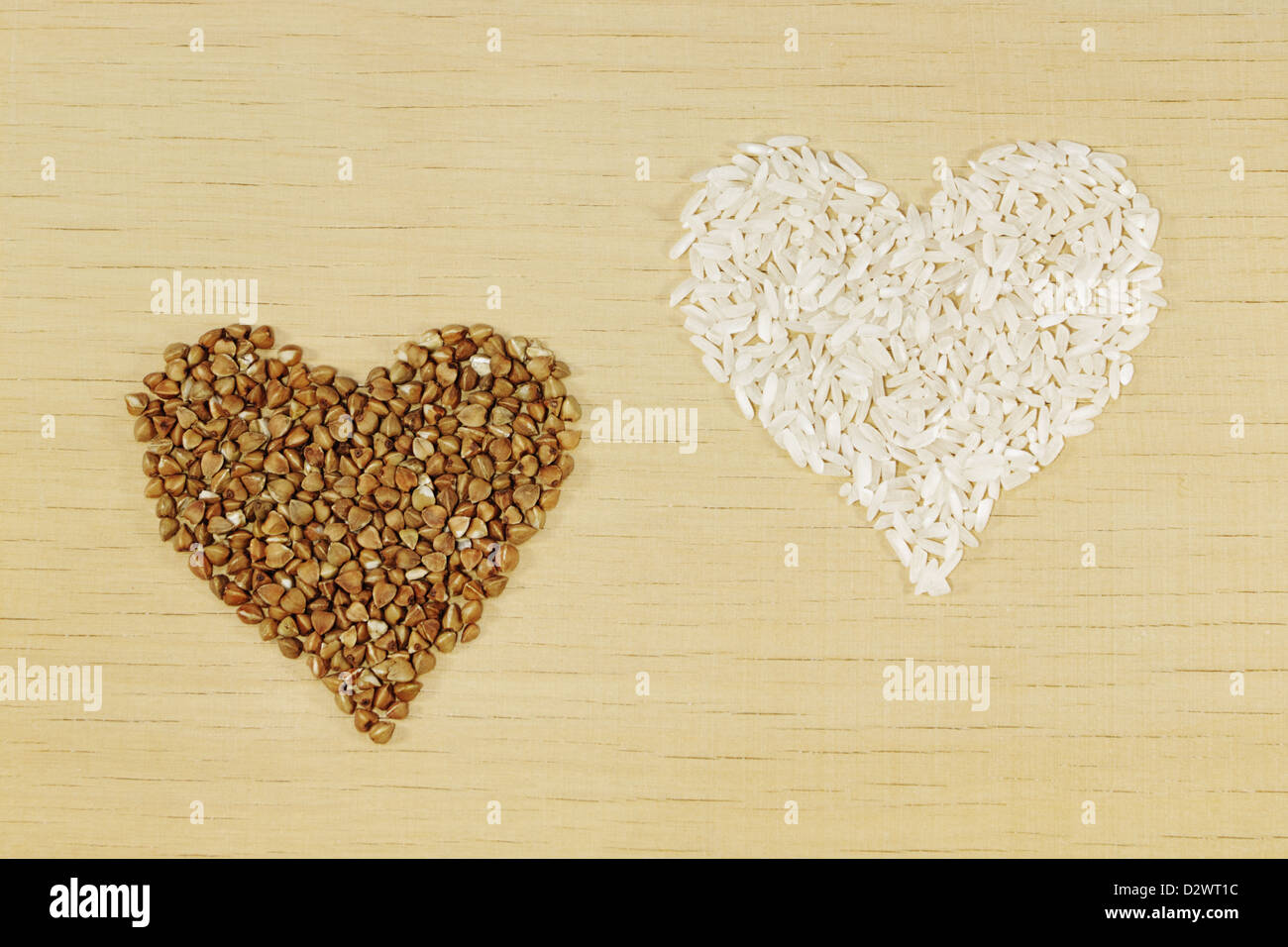 Reis und Buchweizen in Form von Herzen auf Holzplatte Stockfoto