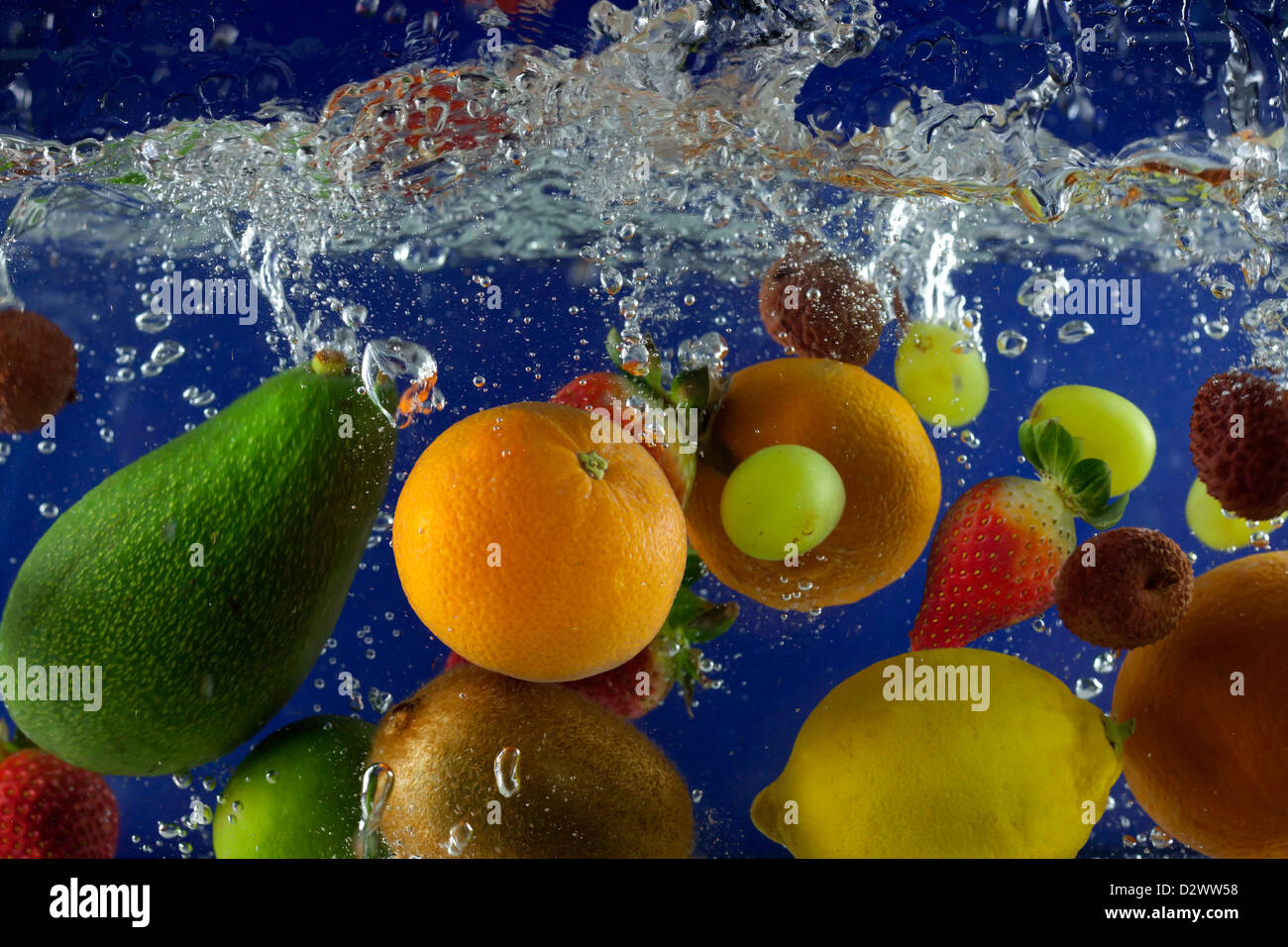 Obst spritzen im Wasser mit Luftblasen vor blauem Hintergrund Stockfoto