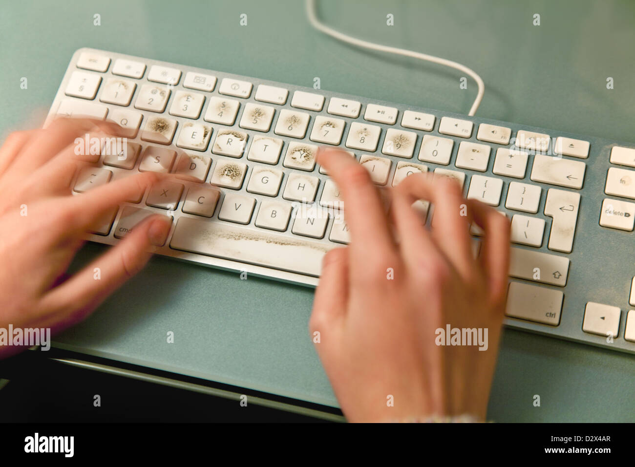 Verschwommene Finger Tippen auf einer schmutzigen Computertastatur Stockfoto