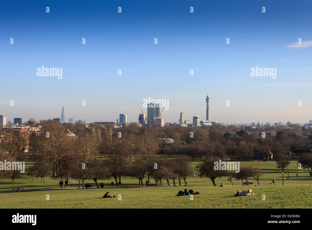 Menschen genießen den sonnigen Frühlingstag in Primrose Hill, einem Park mit herrlichem Blick auf die City of London. Stockfoto