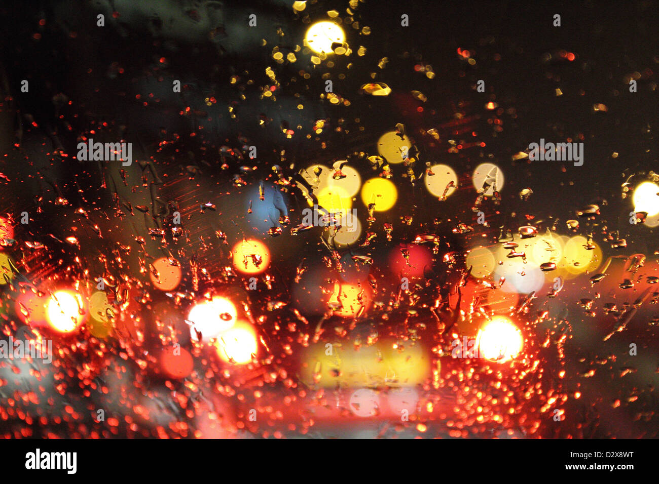 Straße und Auto Lichter durch Regentropfen auf Auto Windschutzscheibe in der Nacht. England-UK Stockfoto