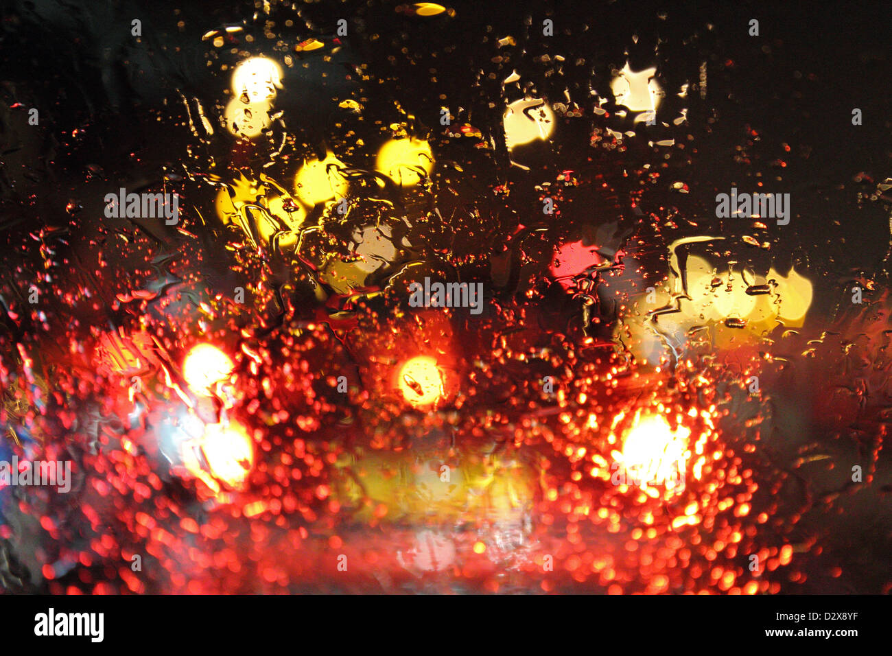 Straße und Auto Lichter durch Regentropfen auf Auto Windschutzscheibe in der Nacht. England-UK Stockfoto