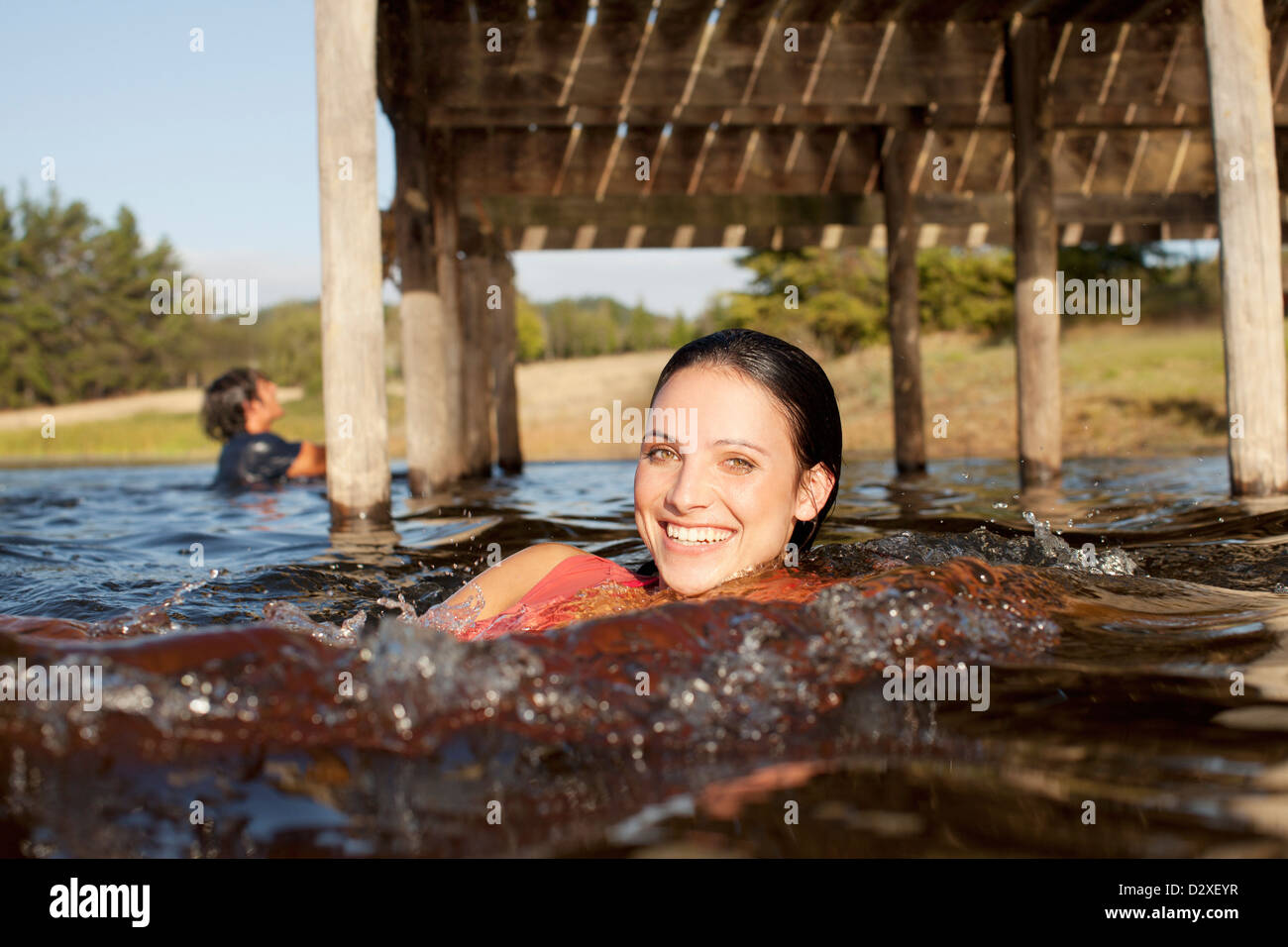 Porträt der lächelnde Frau, Schwimmen im See unter dock Stockfoto