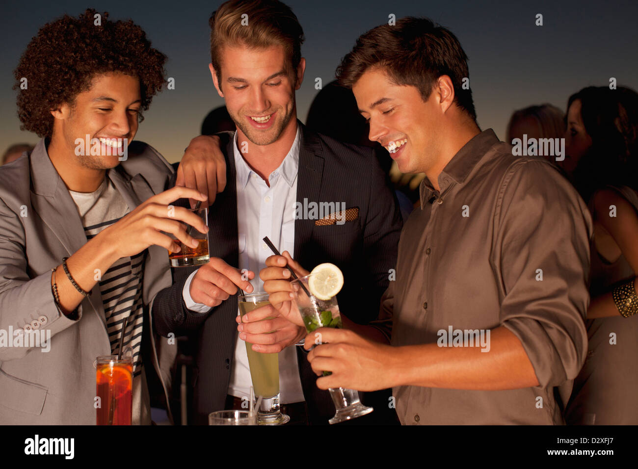Lächelnde Männer Toasten Cocktails in Nachtclub Stockfoto