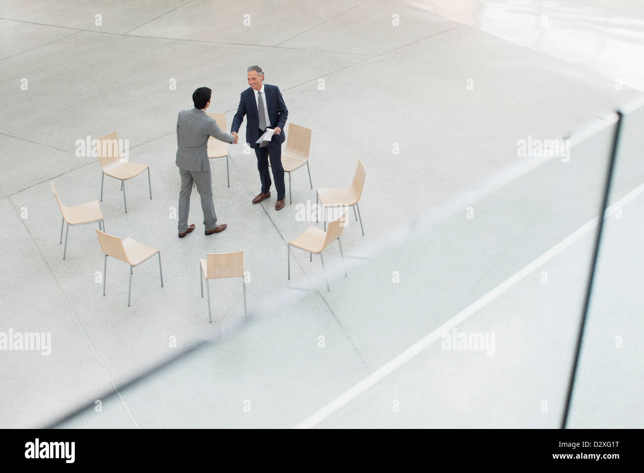 Kreis der Stühle um Geschäftsleute Händeschütteln Stockfoto