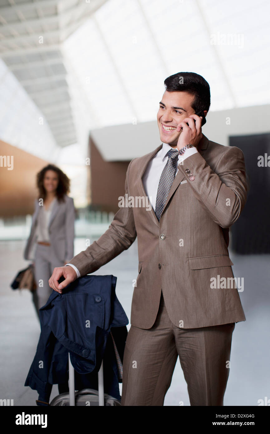 Lächelnde Geschäftsmann reden über Handy am Flughafen Stockfoto