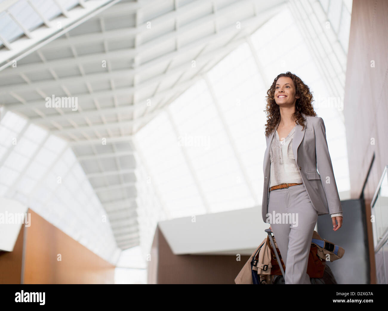 Lächelnd Geschäftsfrau tragen Koffer im Flughafen Stockfoto