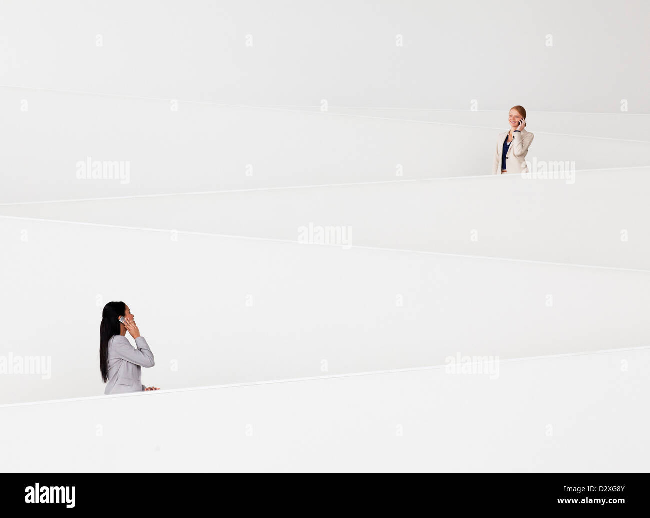 Geschäftsfrauen auf Mobiltelefonen auf moderne Treppe im Gespräch Stockfoto