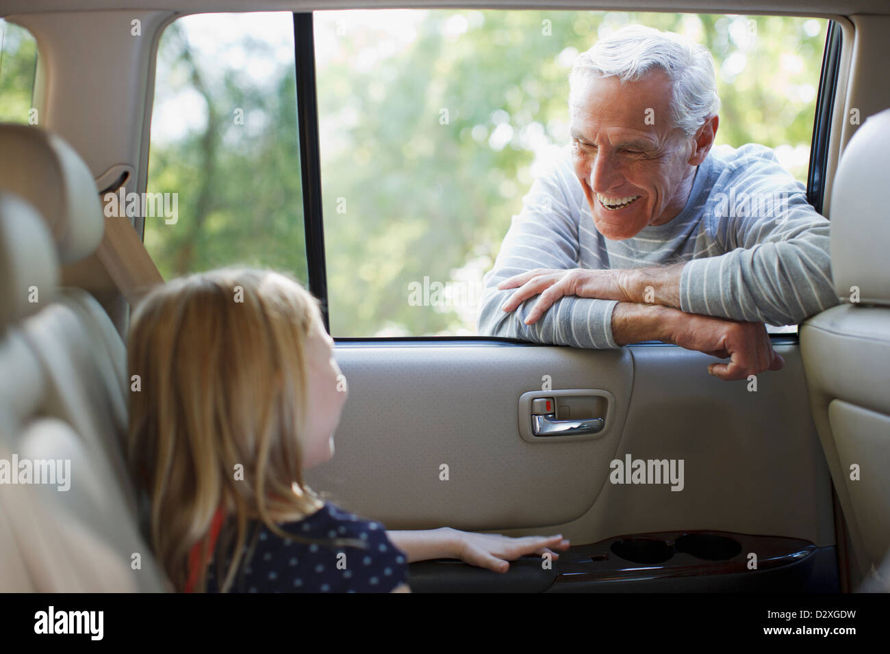 Älterer Mann im Gespräch mit Enkelin im Autofenster Stockfoto