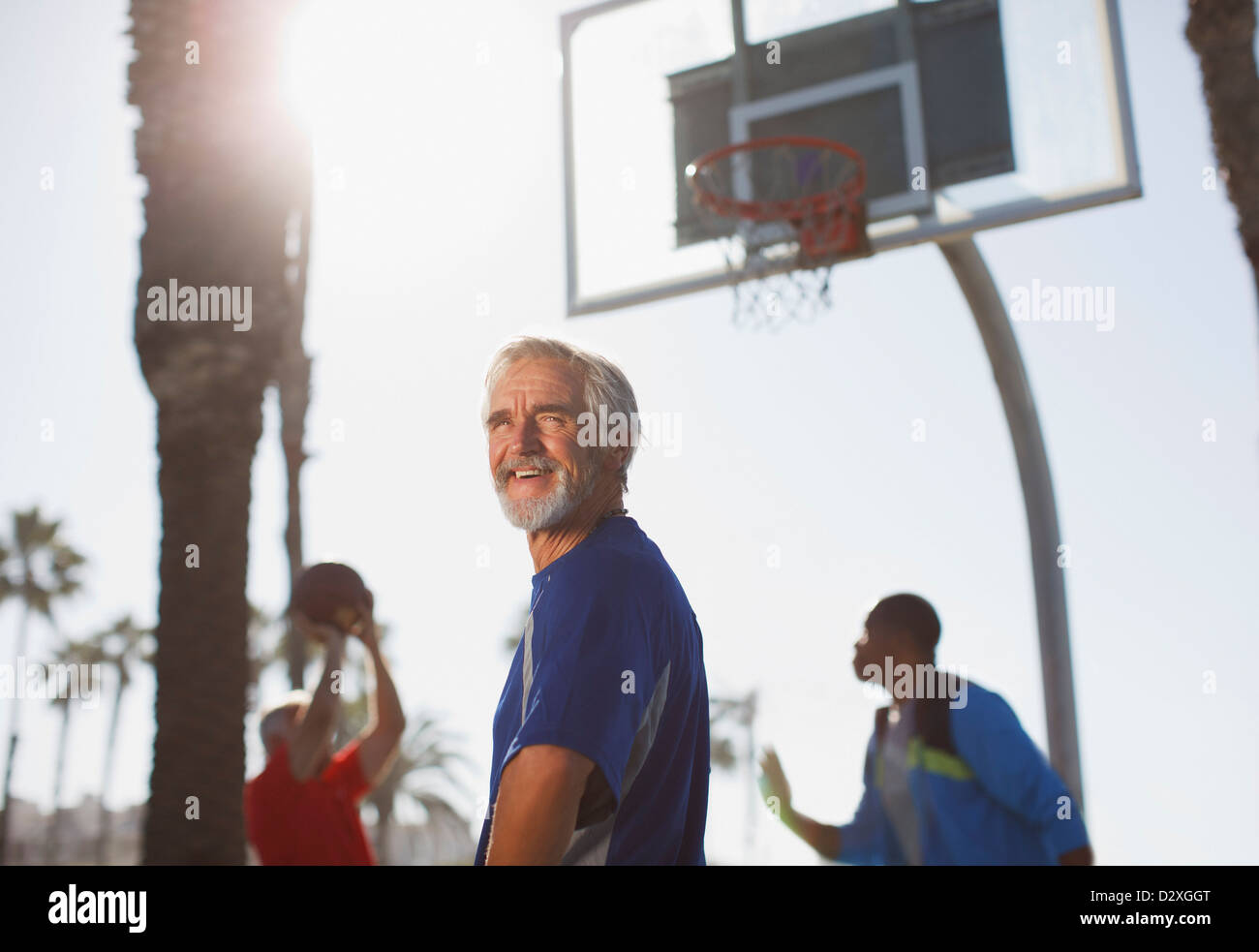 Ältere Männer spielen Basketball auf Platz Stockfoto