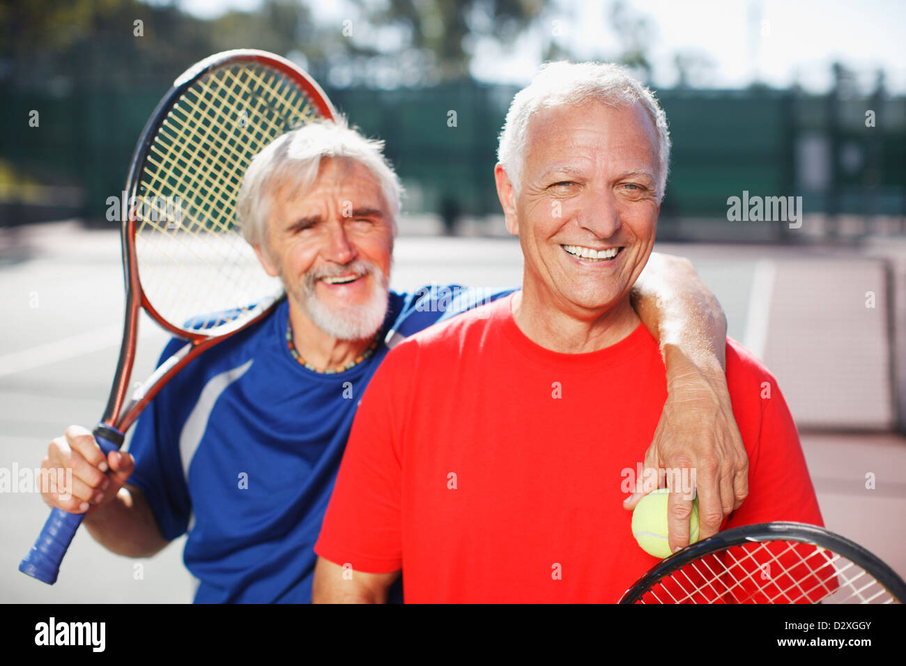 Ältere Männer Lächeln auf Tennisplatz Stockfoto